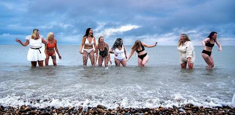 A group of women posing and laughing in the ocean